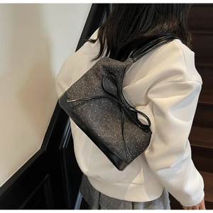 Detail of grey polka dot shoulder bag with black leather bow on an indoor staircase