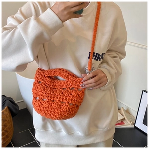 Detail view of orange hand-woven bucket bag showing thick cotton knit texture and hollow design