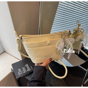 Close-up of pale yellow crossbody bag featuring wrinkled leather and lace pearl bow