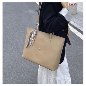 Detail of beige tote bag with pebbled leather texture and decorative checkered scarf