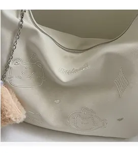 Detail of off-white tote bag with cartoon cat embossing and fluffy brown charm