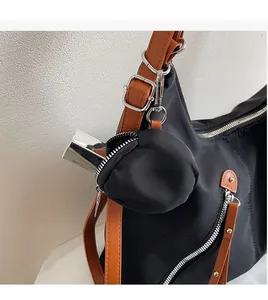 Detail of black nylon tote with brown leather strap and a small round hanging coin pouch