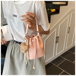 Pink drawstring bucket bag featuring litchi texture leather and a cute plush bear charm