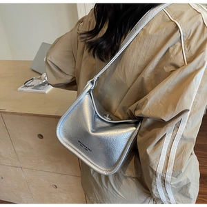 Detail of silver metallic textured crossbody bag with twist lock and logo print on bottom