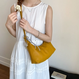 Detail of yellow crescent shoulder bag with silver knot decor and butterfly charm