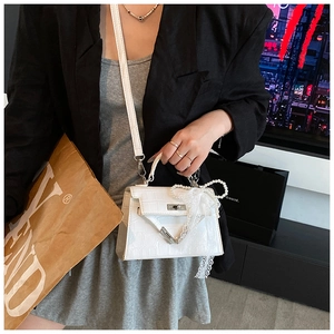 Detail of white crocodile pattern leather handbag with pearl bow and lace streamer