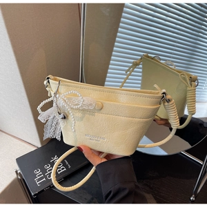 Detail of light yellow bucket bag with lace pearl bow and spiral shoulder strap