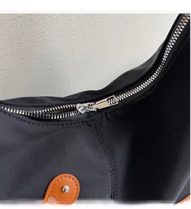 Detailed macro view of the smooth silver metal zipper and leather trim on a black tote bag