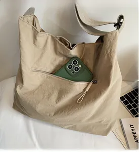 Detail of beige nylon tote bag showing the side zipper pocket and durable fabric