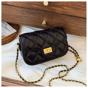 Detail of black quilted leather bag with gold chain strap and metal ball charm