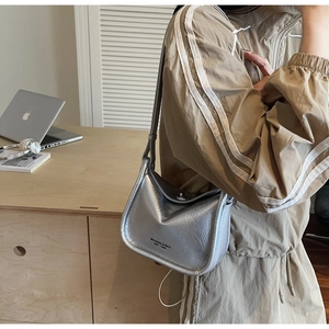 Fashionable metallic silver shoulder bag with textured pleats on a stylish female model