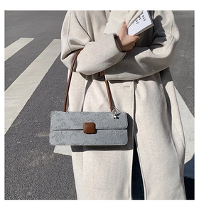 Détail du sac sous le bras gris gaufré avec bandoulière en cuir marron au style urbain