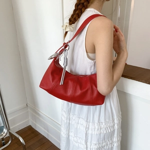 Detail of red pebbled leather hobo bag with silver butterfly charms on white dress