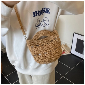 Detail of hand-woven hollow bucket bag featuring sturdy top handles and wide strap