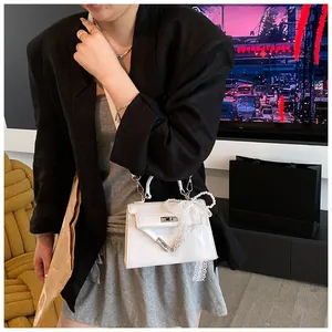 Detail of white crocodile embossed mini Kelly bag with lace pearl bow charm decoration