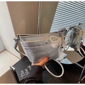 Detail of silver metallic textured crossbody bag with bead chain bow and lace trim