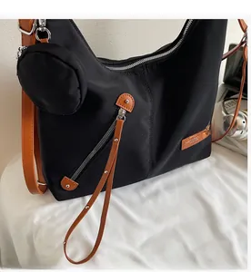 Close-up of black nylon tote bag with brown leather trim and small round coin purse