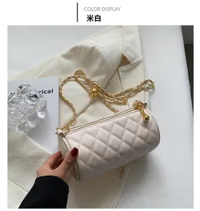 Détail du sac cylindre matelassé crème avec chaîne dorée et décoration de boule en métal