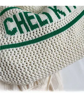 Macro shot of breathable beige knit fabric with green striped trim and letter detail