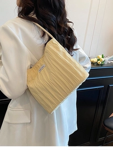 Minimalist cream pleated canvas hobo bag for women worn over a white suit blazer