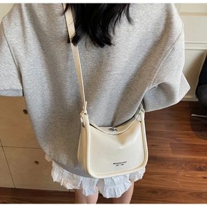 Close-up of cream crossbody bag with silver twist lock and pebble leather texture