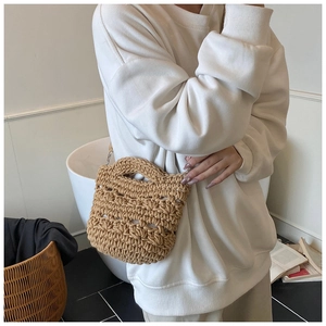 Detailed view of handmade crochet knit texture on this beige summer straw bucket bag