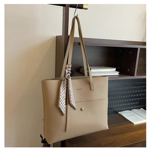 Close-up of beige tote bag featuring lychee grain texture and elegant geometric silk scarf