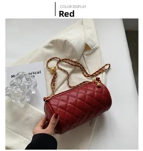 Détail du sac cylindrique rouge matelassé avec bandoulière chaîne sur blazer blanc