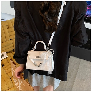 Detailed macro view of white crocodile pattern texture and pearl bow on Kelly style handbag