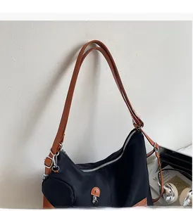Detail of black nylon tote with brown straps, side coin purse, and front zipper pocket