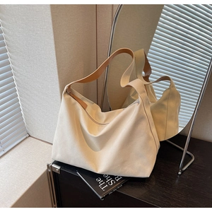 Dettaglio di una borsa tote in tela beige con manici in pelle marrone in una stanza luminosa