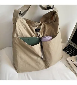 Detail of khaki nylon tote bag showing front pockets storing a tablet and umbrella