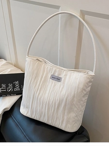 Modern off-white quilted canvas shoulder bag with a cylindrical strap and brand tag