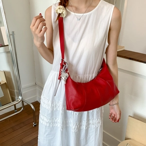 Detail of red hobo bag with lychee grain leather and silver metal butterfly pendant
