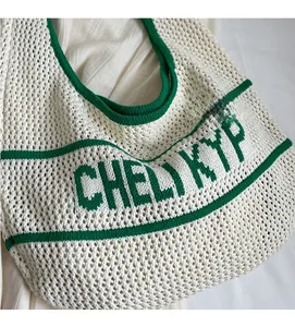 Detail view of white knit tote bag with green stripes and woven lettering on the front surface