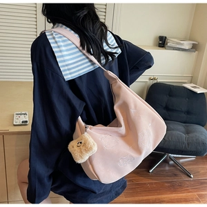 Detailed embroidery of a white cat on a pink canvas shoulder bag with a plush charm