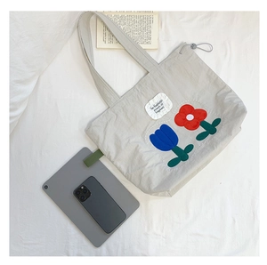 Detail of grey canvas tote bag with floral embroidery and adjustable drawstring closure