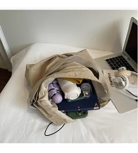 Macro detail of spacious interior showing umbrella, tablet, and bottle in khaki bucket bag