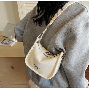 Detail of minimalist beige pleated leather crossbody bag with metallic rotary lock and logo