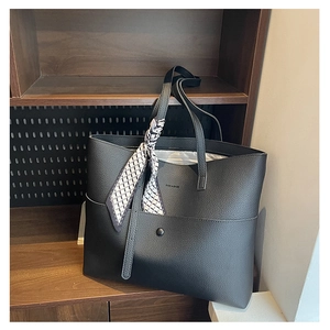 Detail of black tote bag with lychee texture, silk scarf decoration, and front pocket