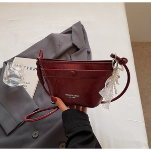 Detail of burgundy pleated leather bucket bag with pearl and lace pendant decoration