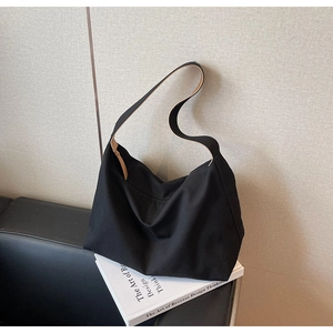 Dettaglio della borsa hobo nera su libri che mostra la capienza e lo stile minimalista