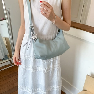 Detail of light blue crescent hobo bag with silver heart charm and pebbled texture