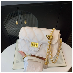 Close-up of quilted cream crossbody bag featuring a gold chain strap and metal ball detail