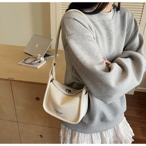 Detail of cream white leather shoulder bag with silver rotating clasp and soft texture