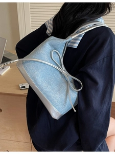 Light blue denim shoulder bag with silver leather bow and trim in a lifestyle office setting