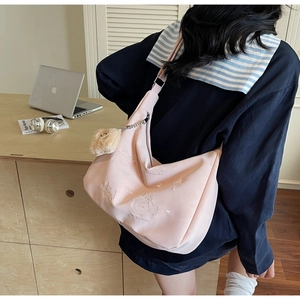 Pink crossbody bag with cat embossed pattern and wide strap shown in an office setting