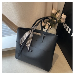 Close-up of black lychee grain tote bag with geometric silk scarf and embossed logo