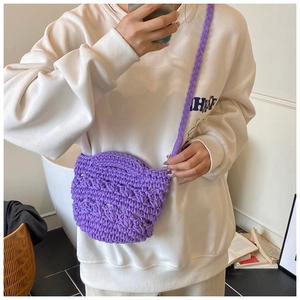 Detail of purple hand-knitted crossbody bucket bag with thick braided strap on model