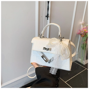 Detail of white crocodile texture handbag with lace ribbon and pearl chain charm